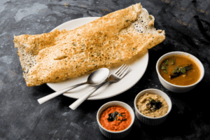 A plate of South Indian dosa served with coconut chutney and sambar.